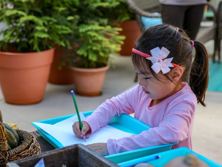 child sitting at table writing 