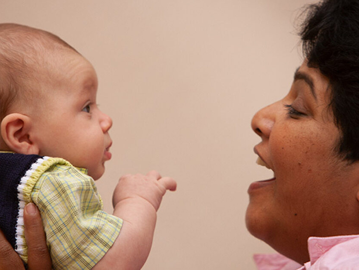 Infant being held by a teacher while exchanging happy expressions at day care 