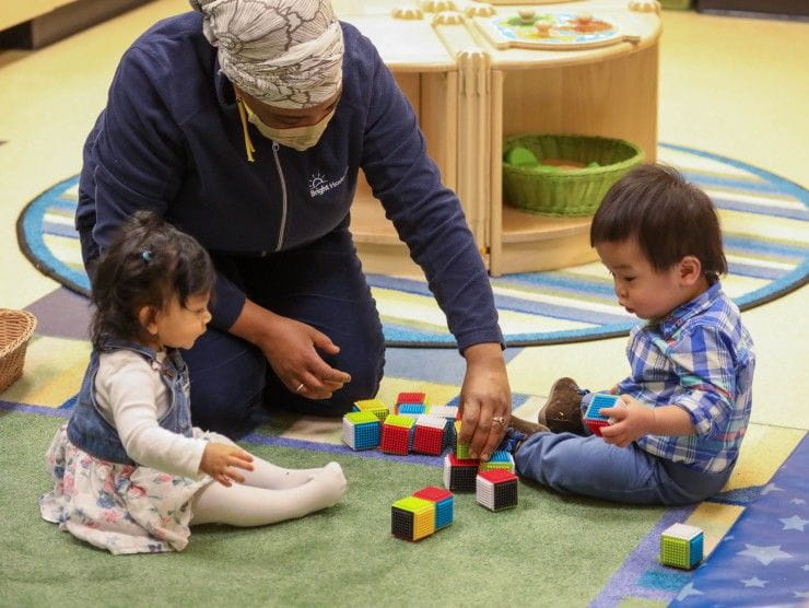 teacher playing with children on floor 