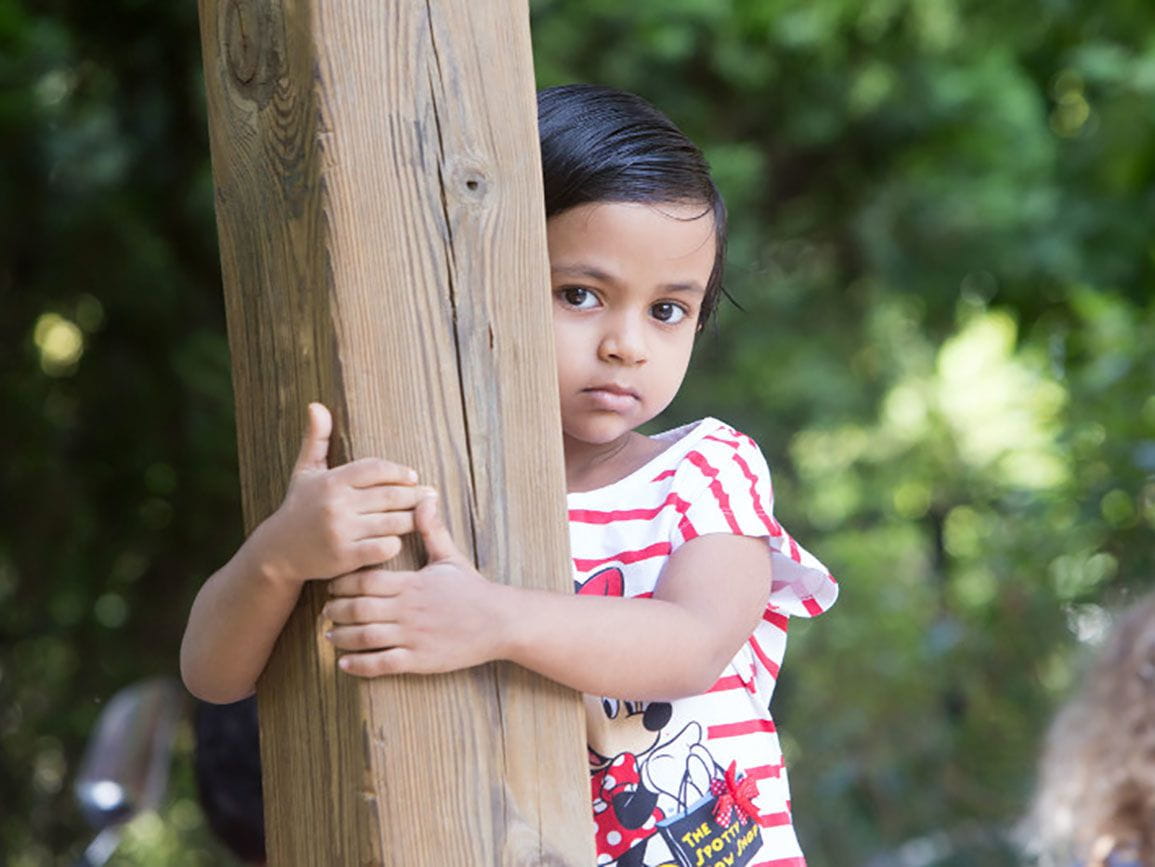 Girl having a toddler tantrum and hugging a wooden pole